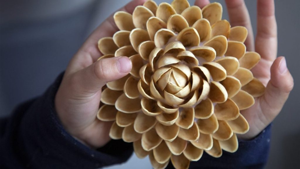 Child holds a DIY candle holder made of pistachio shells