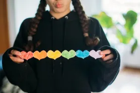 girl holding a paper chain of rainbow hearts