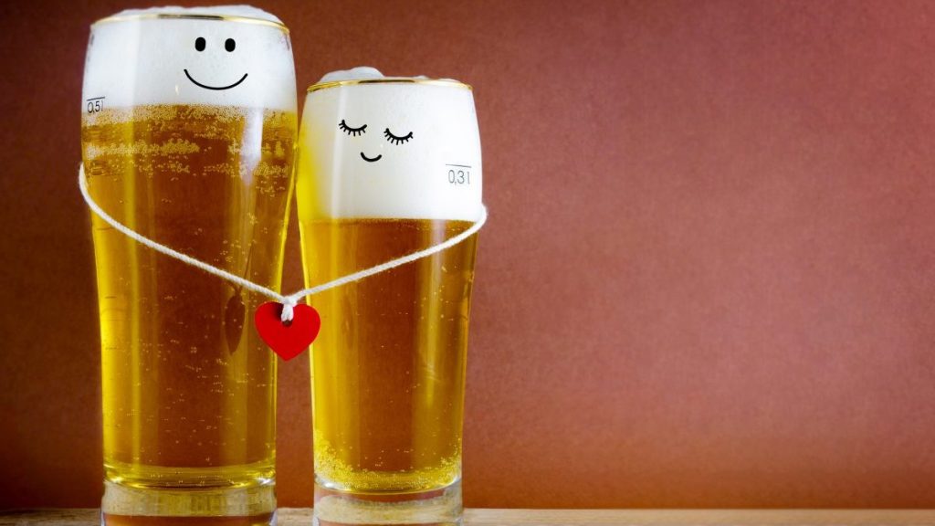 Two glasses of beer with Painted happy couple and red heart on a string. Valentine day, happy couple concept. Copy space