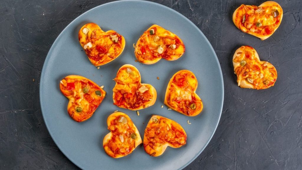 Foods for Valentine's Day. Miniature pizza at one bite, cheese and fresh vegetables.