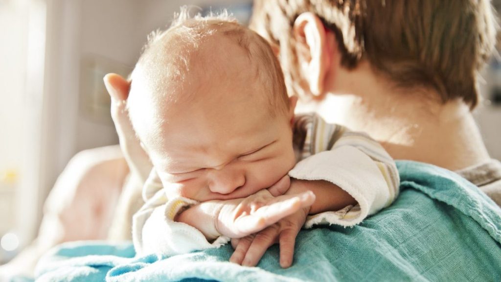 Father holding up newborn baby to burp