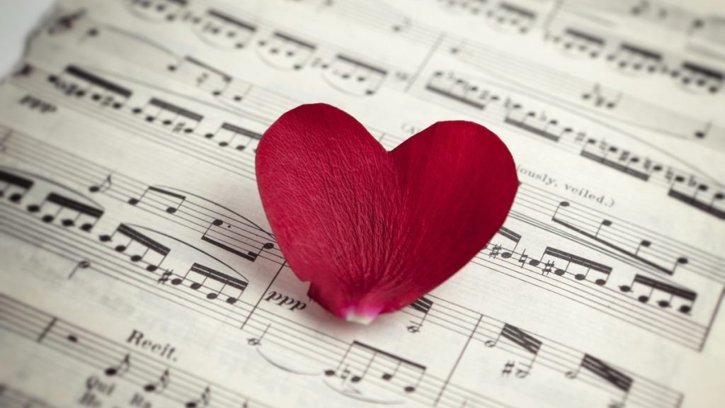 Heart shaped rose petal on music sheet. Love song concept.