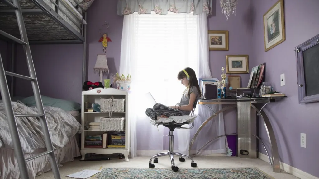 Young girl being homeschooled studying through technology at home