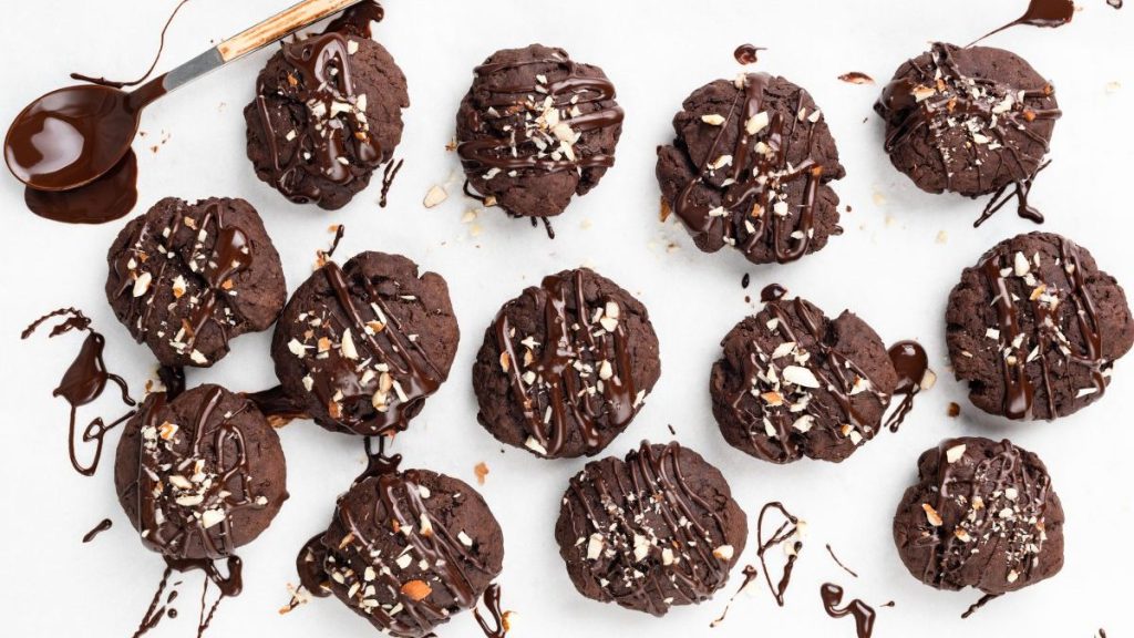 Homemade chocolate blobbs with chopped almonds and chocolate glaze on white background, top view