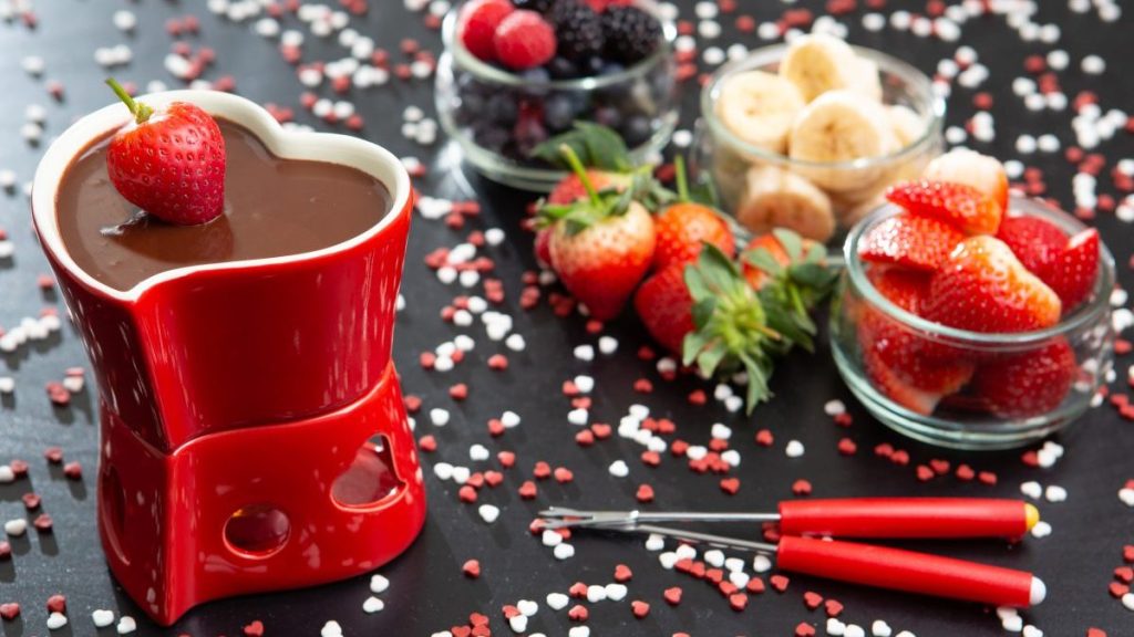Table set for a romantic occasion on Valentine's Day with Chocolate Fondue with a strawberry splashing on the chocolate.