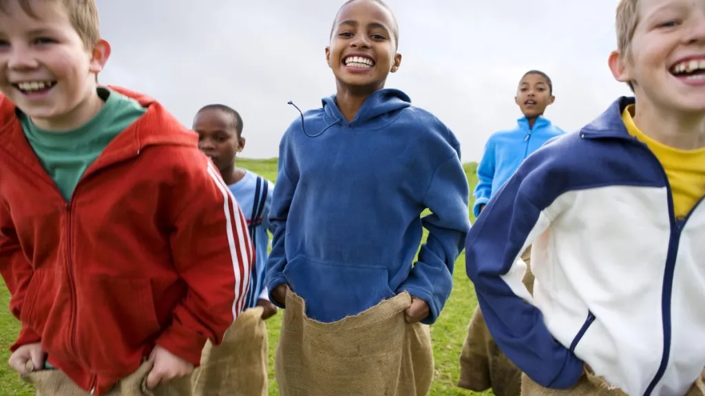 Group of boys aged 10-13 having a sack race outdoors