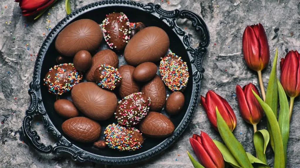 Chocolate Easter egg truffles with dessert sprinkles and red tulips
