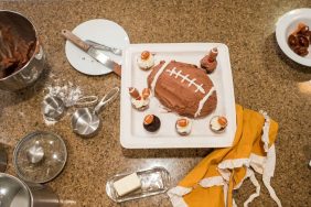 football shaped cake with plastic footballs on kitchen counter with cooking supplies