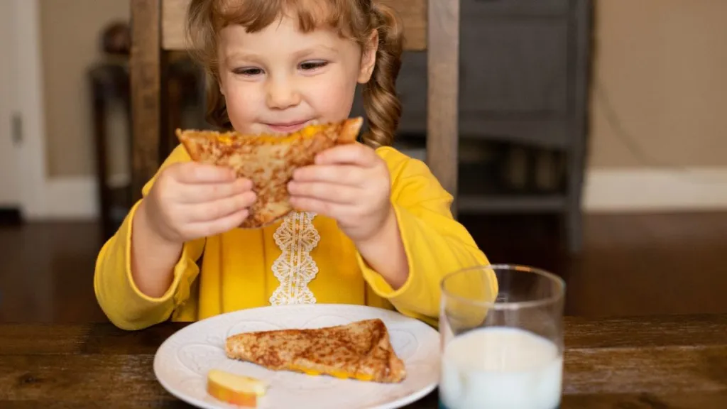 Young girl eating a grilled cheese sandwich.