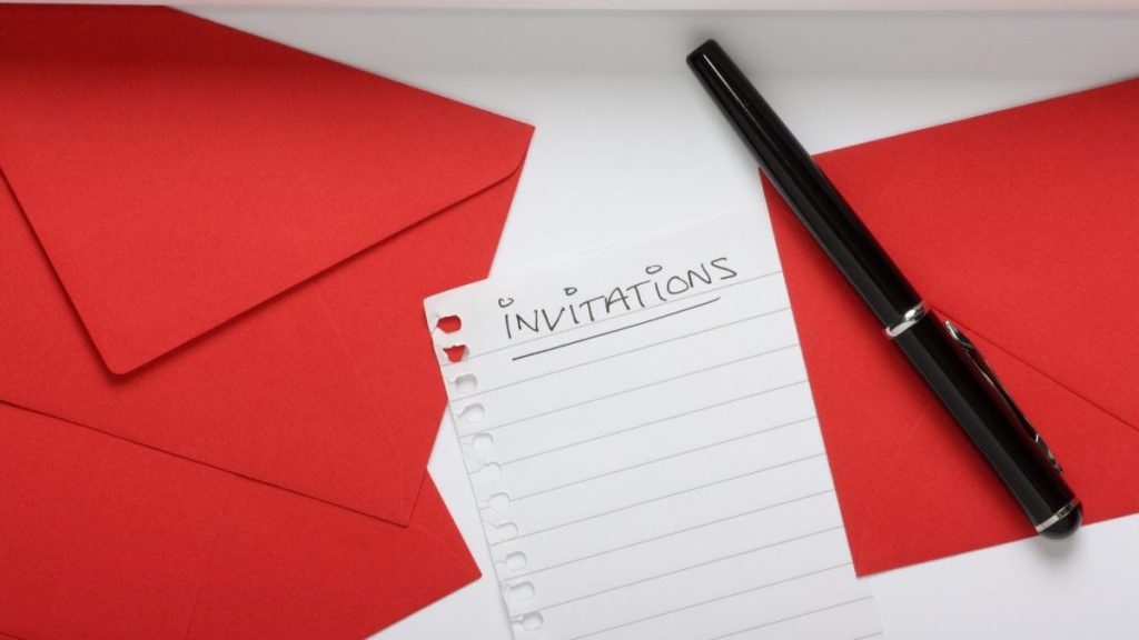A blank Invitations list with a writing pad,red envelopes and a fountain pen to get started