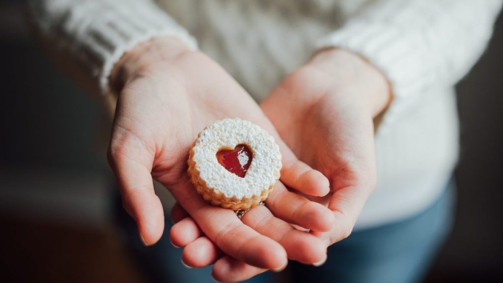 Close up of hands cupped showing a Linzer cookie.