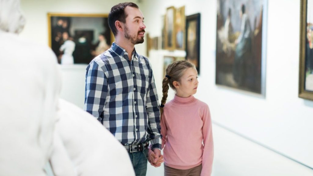Young father and little daughter looking at expositions in museum