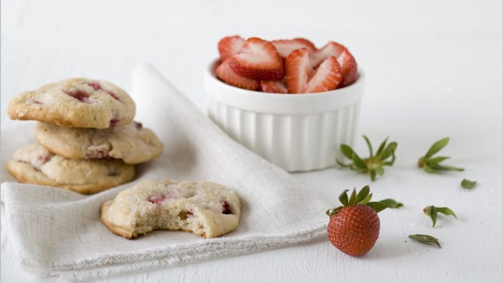 Strawberry shortcake cookies with fresh strawberries on white napkin.