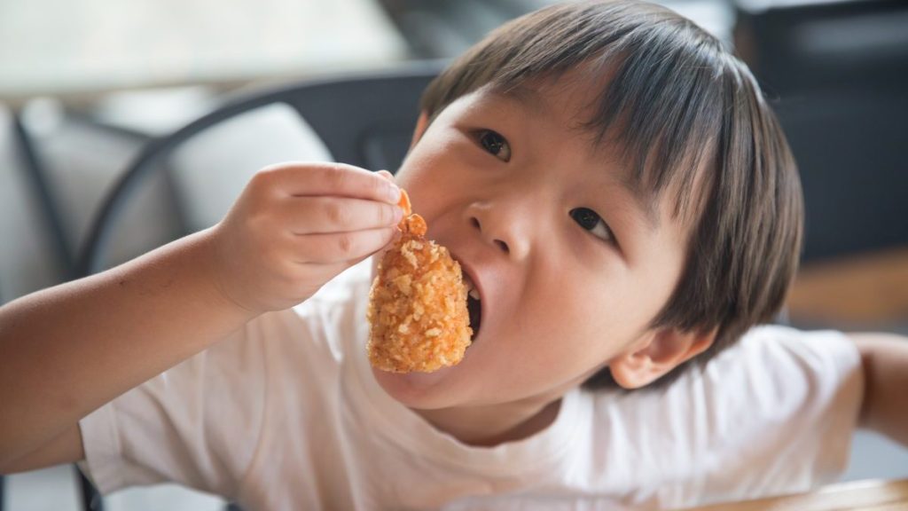 An Asian boy enjoys having crispy fried shrimp tempura.
