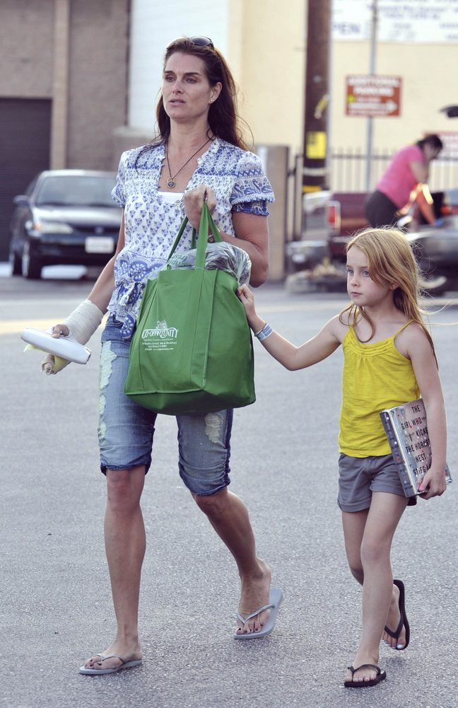 Brooke Shields, blue and white print top, ripped denim capris, flip flops, book, tote bag