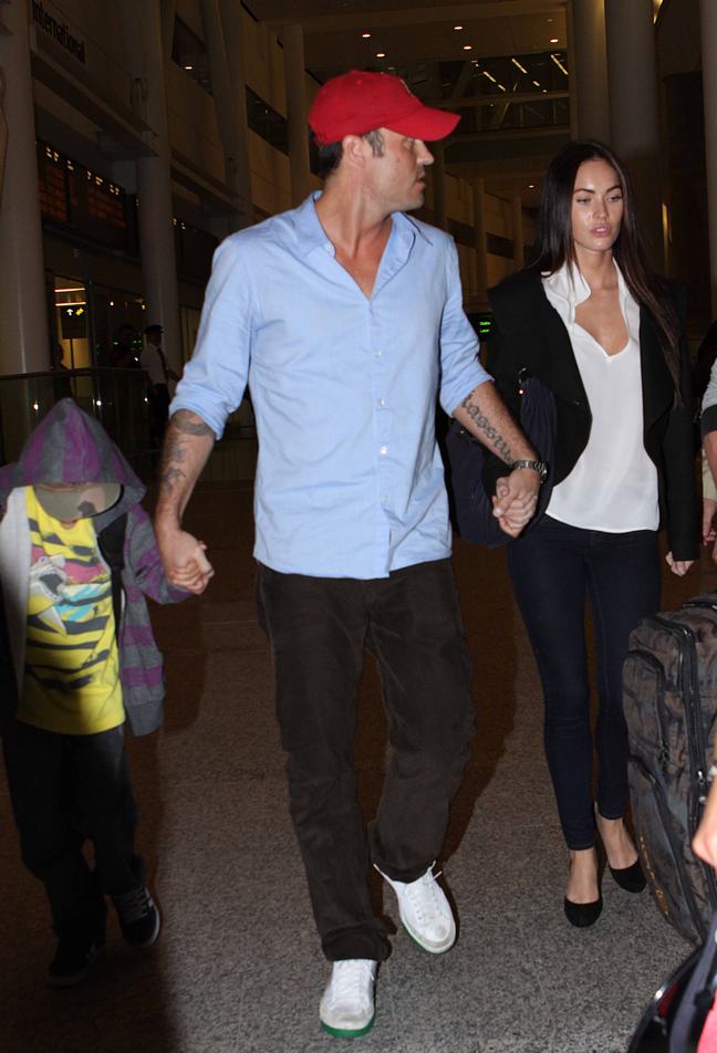 Brian Austin Green, light blue shirt, red baseball hat, black jeans, white shoes, Megan Fox, skinny jeans, white shirt, black ballet slippers, black jacket